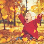 happy little child, baby girl laughing and playing in autumn