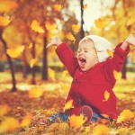 happy little child, baby girl laughing and playing in autumn