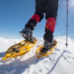 Hiker snowshoeing in winter mountains during sunny day